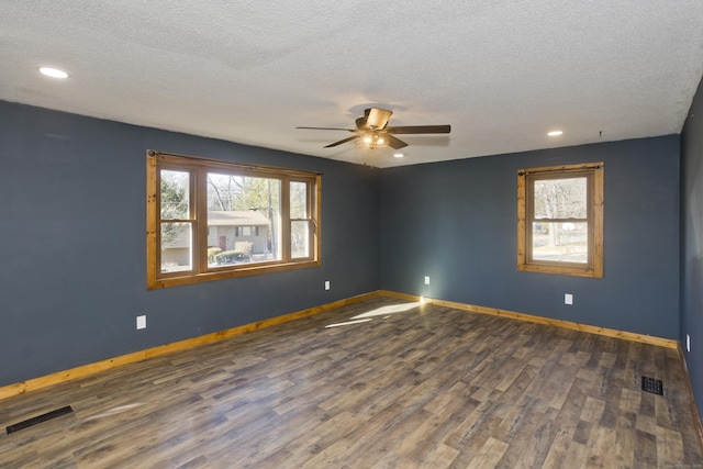 spare room featuring visible vents, a textured ceiling, baseboards, and wood finished floors