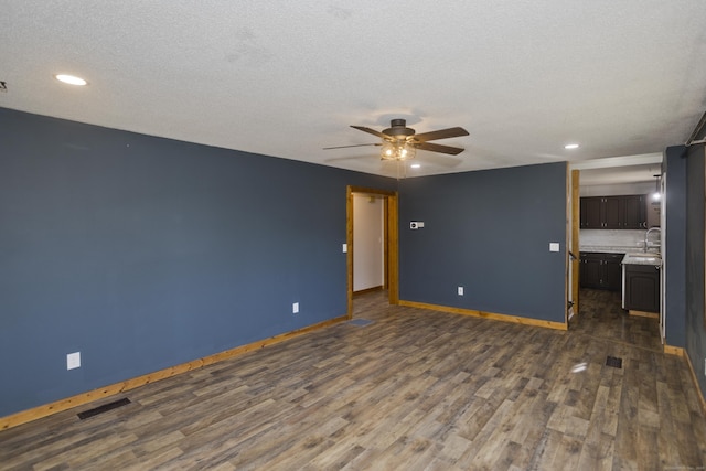 unfurnished living room featuring a ceiling fan, baseboards, visible vents, dark wood finished floors, and a sink