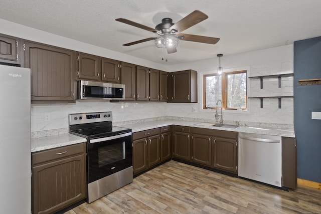 kitchen featuring dark brown cabinets, appliances with stainless steel finishes, open shelves, and a sink