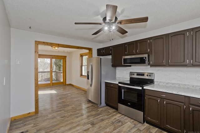 kitchen featuring light countertops, light wood-style floors, dark brown cabinetry, and stainless steel appliances