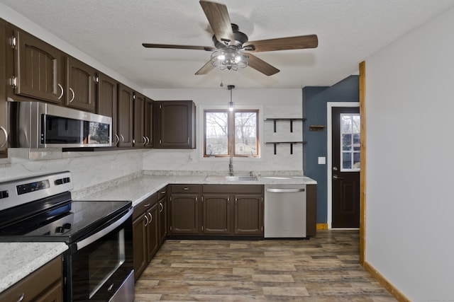 kitchen with backsplash, dark brown cabinetry, appliances with stainless steel finishes, wood finished floors, and a sink