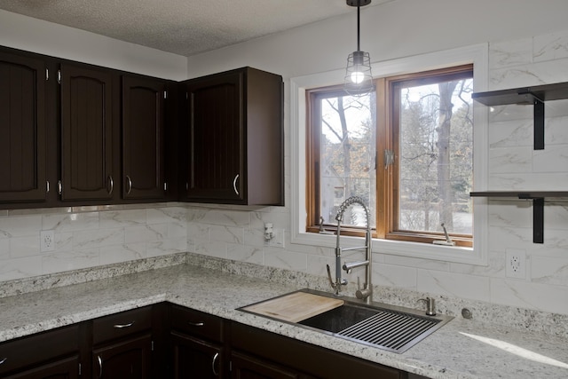 kitchen with a sink, plenty of natural light, pendant lighting, and light countertops