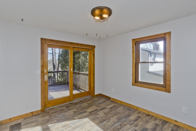 empty room featuring visible vents, baseboards, and wood finished floors