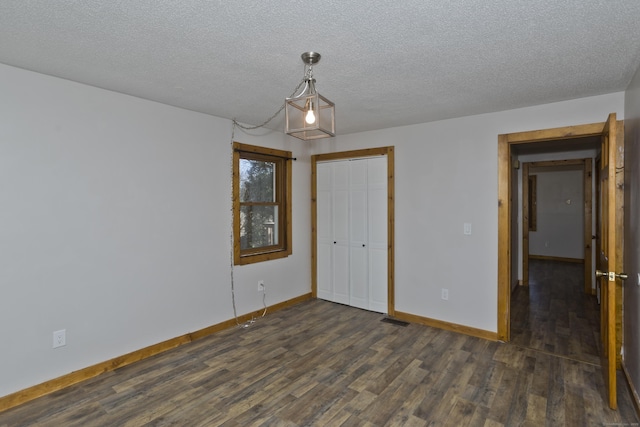 unfurnished bedroom with a closet, baseboards, and dark wood-style flooring