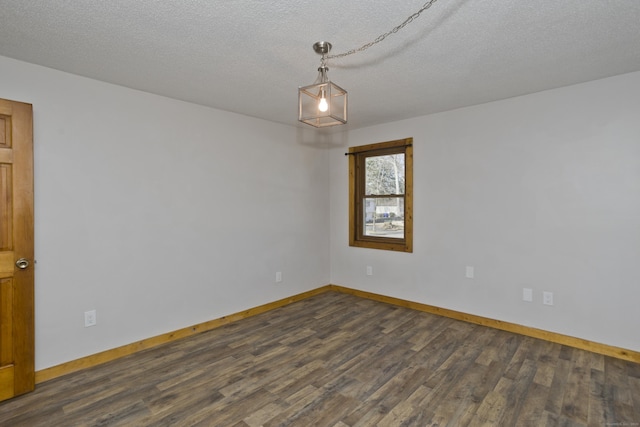 spare room featuring dark wood-style floors, a textured ceiling, and baseboards