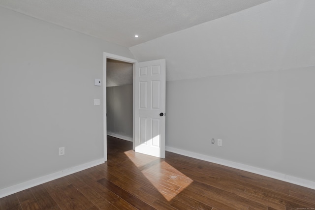 unfurnished room with baseboards, wood-type flooring, a textured ceiling, and lofted ceiling