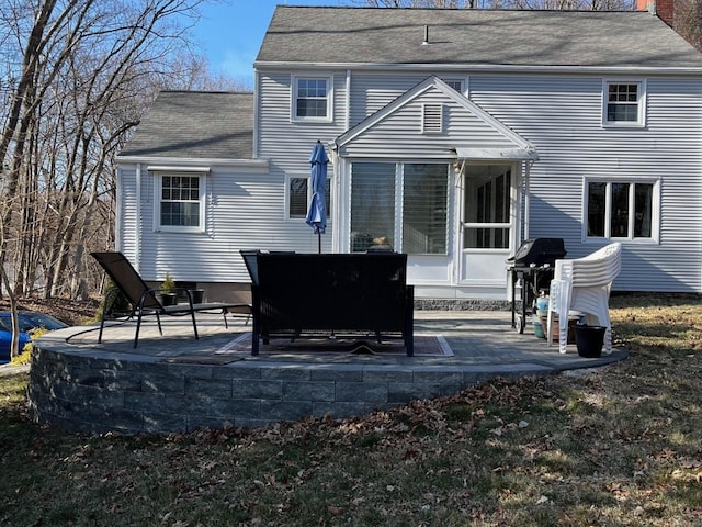 rear view of property featuring a patio and roof with shingles