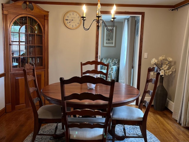 dining space featuring baseboards, an inviting chandelier, wood finished floors, and ornamental molding