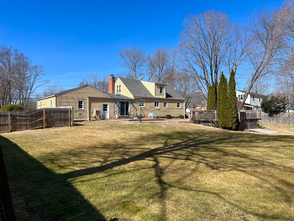 back of house with a yard, a patio area, a chimney, and fence