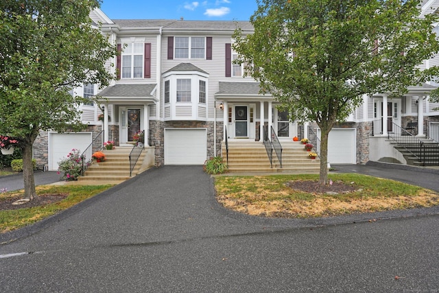 view of property featuring stone siding, an attached garage, and driveway