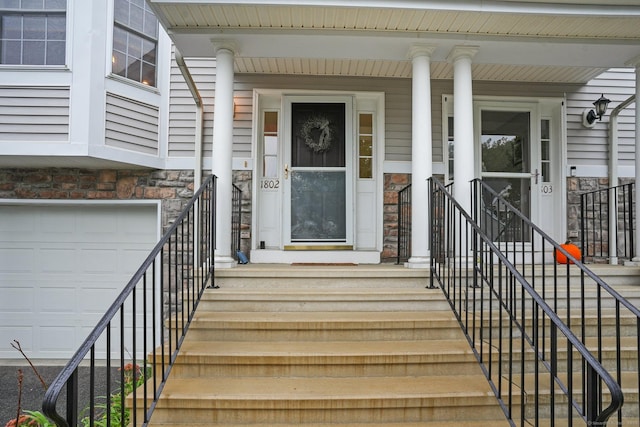 doorway to property featuring an attached garage and stone siding