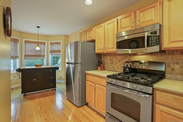 kitchen with backsplash, light brown cabinetry, light countertops, light wood-style flooring, and appliances with stainless steel finishes