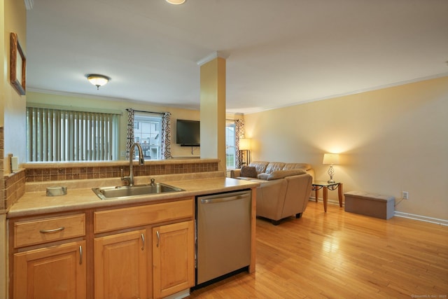 kitchen featuring a sink, ornamental molding, open floor plan, and stainless steel dishwasher