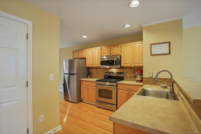 kitchen featuring light wood-style flooring, a sink, decorative backsplash, light countertops, and appliances with stainless steel finishes