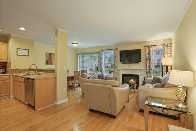 living area with a glass covered fireplace, recessed lighting, light wood-type flooring, and ornamental molding