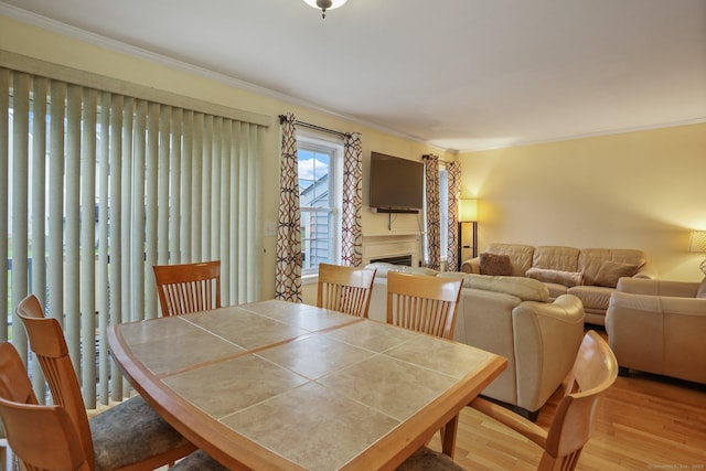 dining room featuring a fireplace, crown molding, and wood finished floors