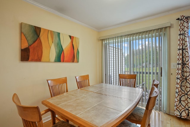 dining area with wood finished floors and ornamental molding