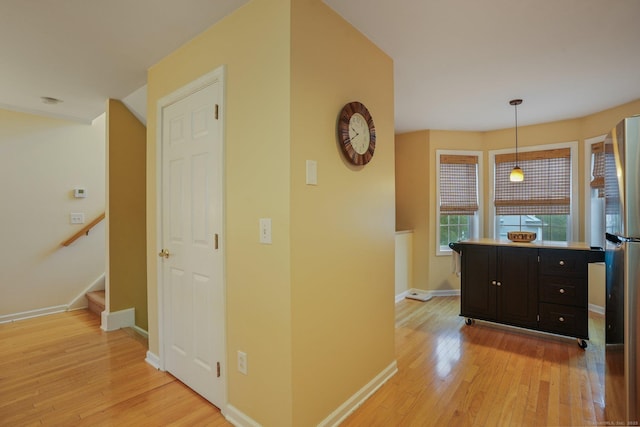 hallway featuring stairway, baseboards, and light wood-style flooring