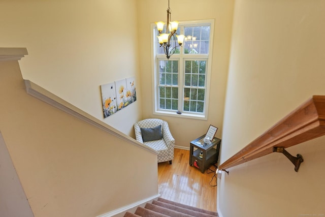 staircase with plenty of natural light, baseboards, an inviting chandelier, and wood finished floors