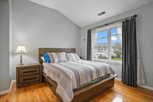 bedroom with lofted ceiling, baseboards, visible vents, and light wood-type flooring