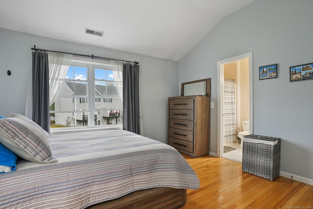 bedroom featuring baseboards, visible vents, ensuite bath, vaulted ceiling, and hardwood / wood-style flooring