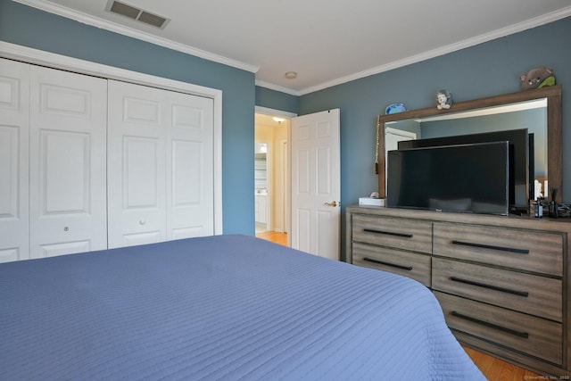 bedroom with crown molding, wood finished floors, visible vents, and a closet