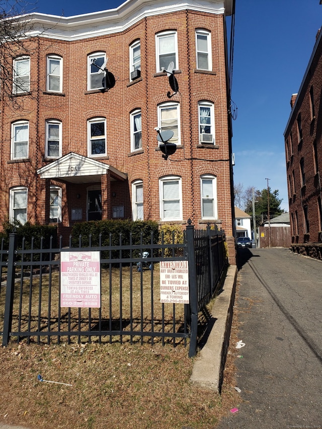 view of front of house featuring brick siding and fence