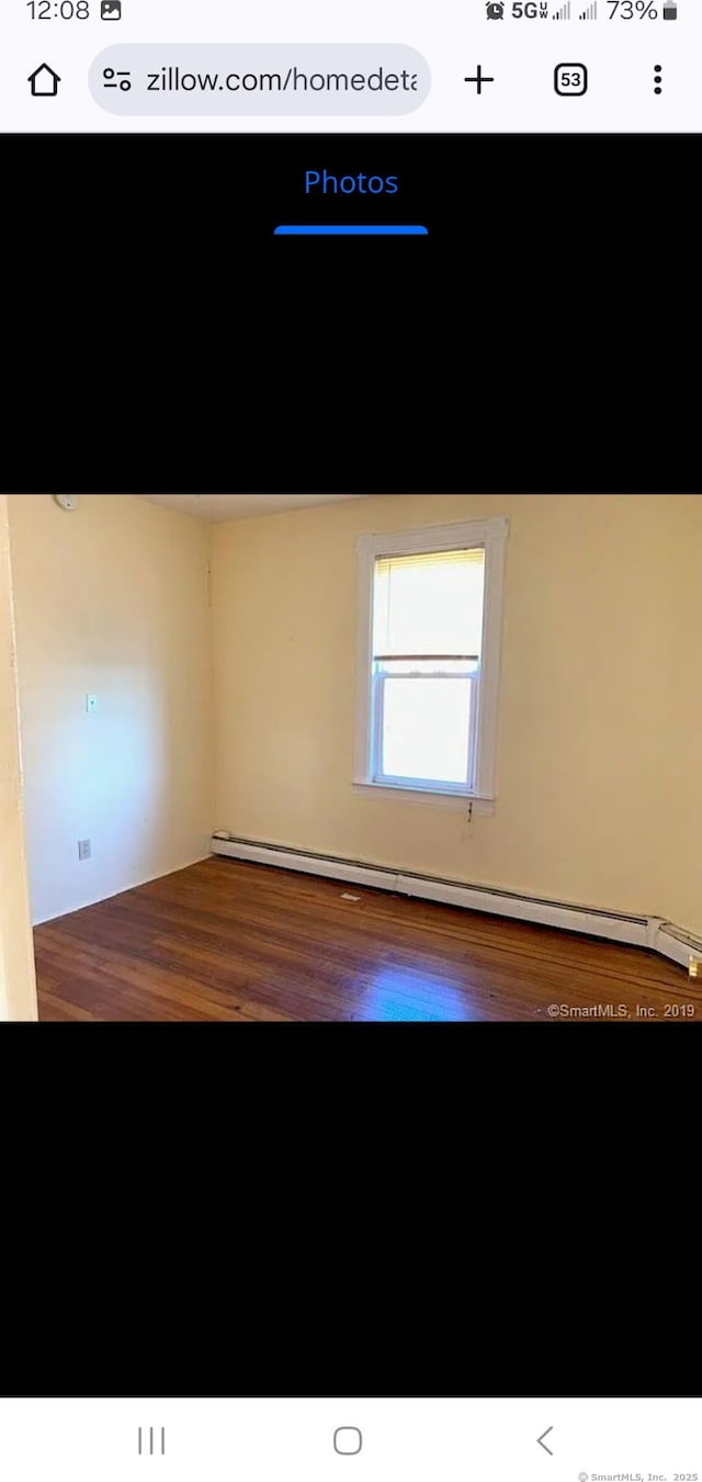 unfurnished room featuring wood finished floors and a baseboard radiator