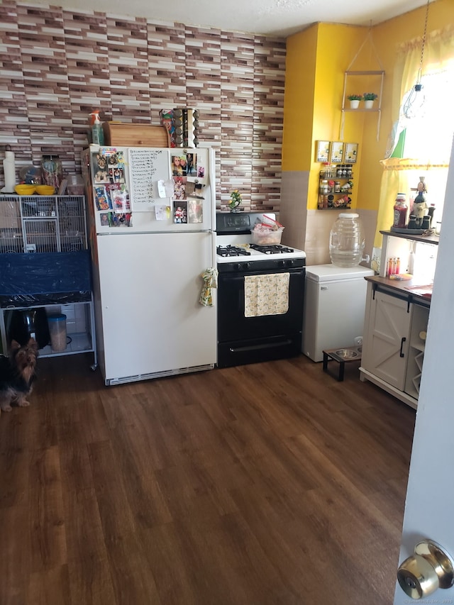 kitchen featuring dark wood-style floors, hanging light fixtures, range with gas cooktop, and freestanding refrigerator