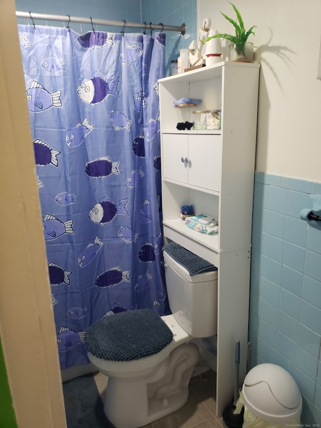 full bathroom featuring tile patterned floors, a shower with curtain, toilet, and tile walls