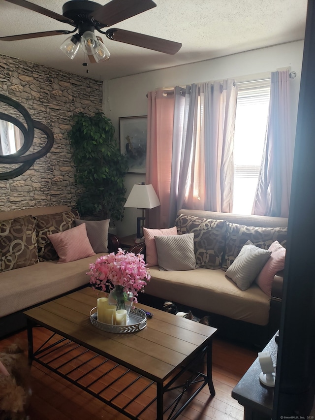 living room with a textured ceiling, light wood-style floors, and ceiling fan