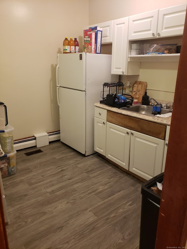 kitchen featuring a sink, dark wood-style floors, freestanding refrigerator, white cabinets, and light countertops