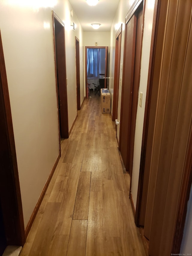 hall featuring light wood-type flooring and baseboards