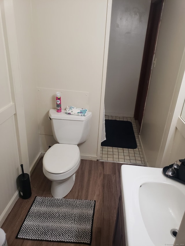 bathroom featuring a sink, baseboards, toilet, and wood finished floors