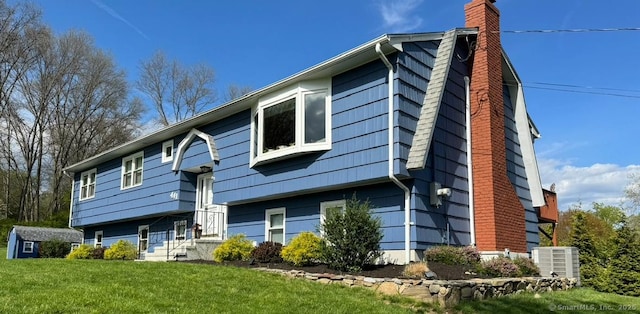 exterior space with central AC unit, a chimney, and a yard