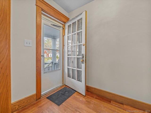 doorway featuring baseboards and wood finished floors