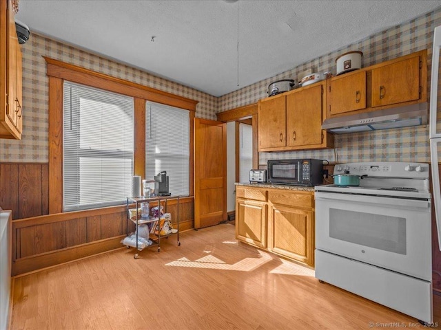 kitchen with wallpapered walls, black microwave, under cabinet range hood, and white range with electric cooktop