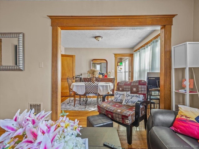 living room with visible vents, a textured ceiling, and wood finished floors