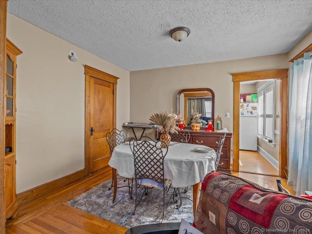 dining room featuring baseboards, a textured ceiling, and hardwood / wood-style flooring