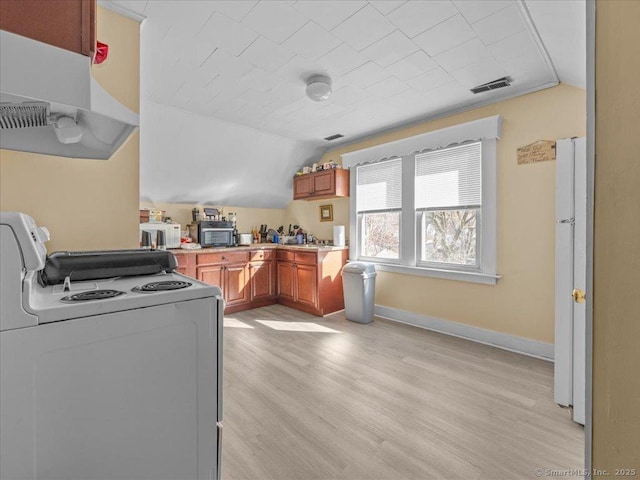 kitchen with visible vents, brown cabinets, range with electric cooktop, lofted ceiling, and white microwave