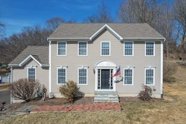 colonial house with a front yard and roof with shingles