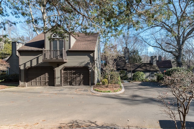 view of front of property featuring driveway, a shingled roof, and a garage