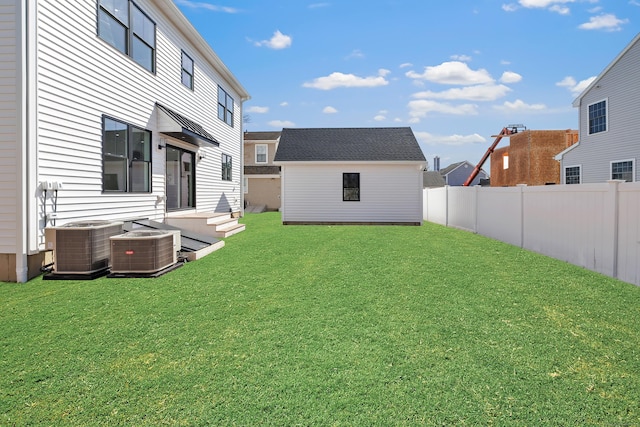 view of yard with central air condition unit, an outdoor structure, and fence