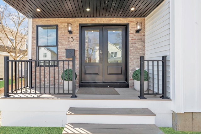 property entrance with brick siding, covered porch, and french doors