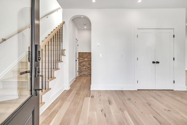 entryway with baseboards, stairs, recessed lighting, light wood-style floors, and arched walkways