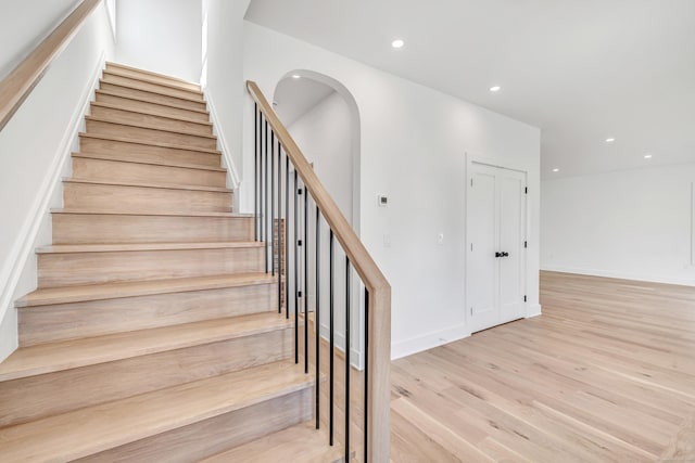 stairs featuring arched walkways, recessed lighting, baseboards, and wood finished floors