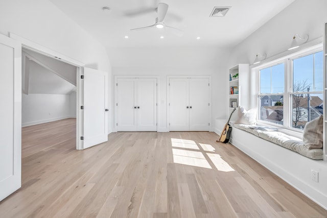 interior space featuring visible vents, multiple closets, light wood finished floors, baseboards, and vaulted ceiling