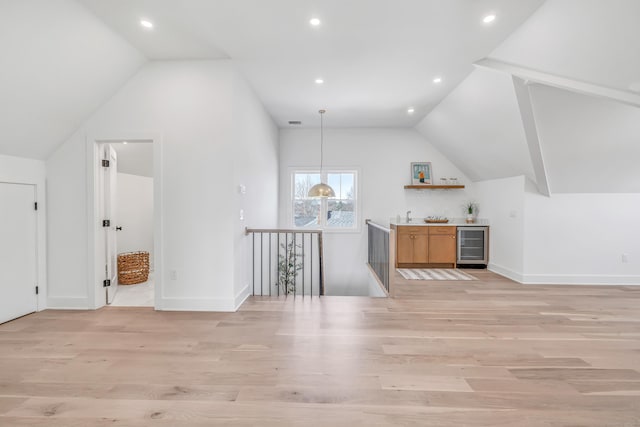 bonus room with vaulted ceiling, a dry bar, beverage cooler, and light wood finished floors