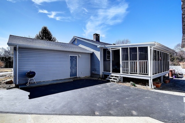 rear view of house with a chimney and a sunroom