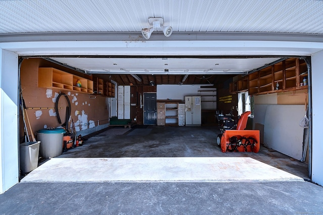 garage featuring driveway and white fridge with ice dispenser